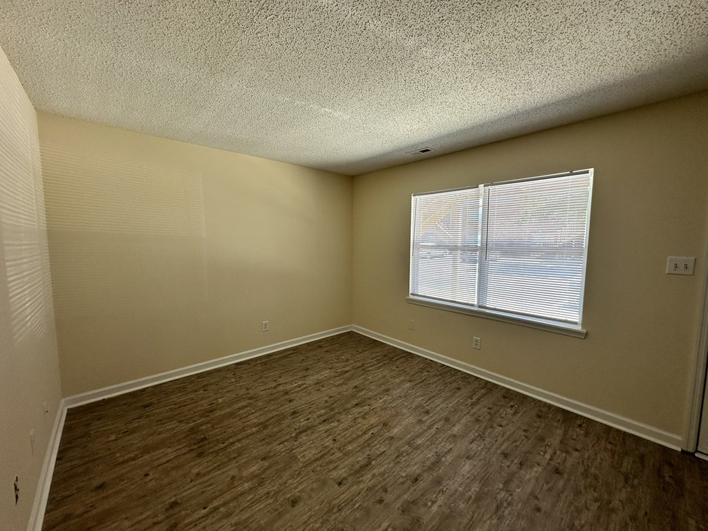 an empty living room with wood flooring and a window