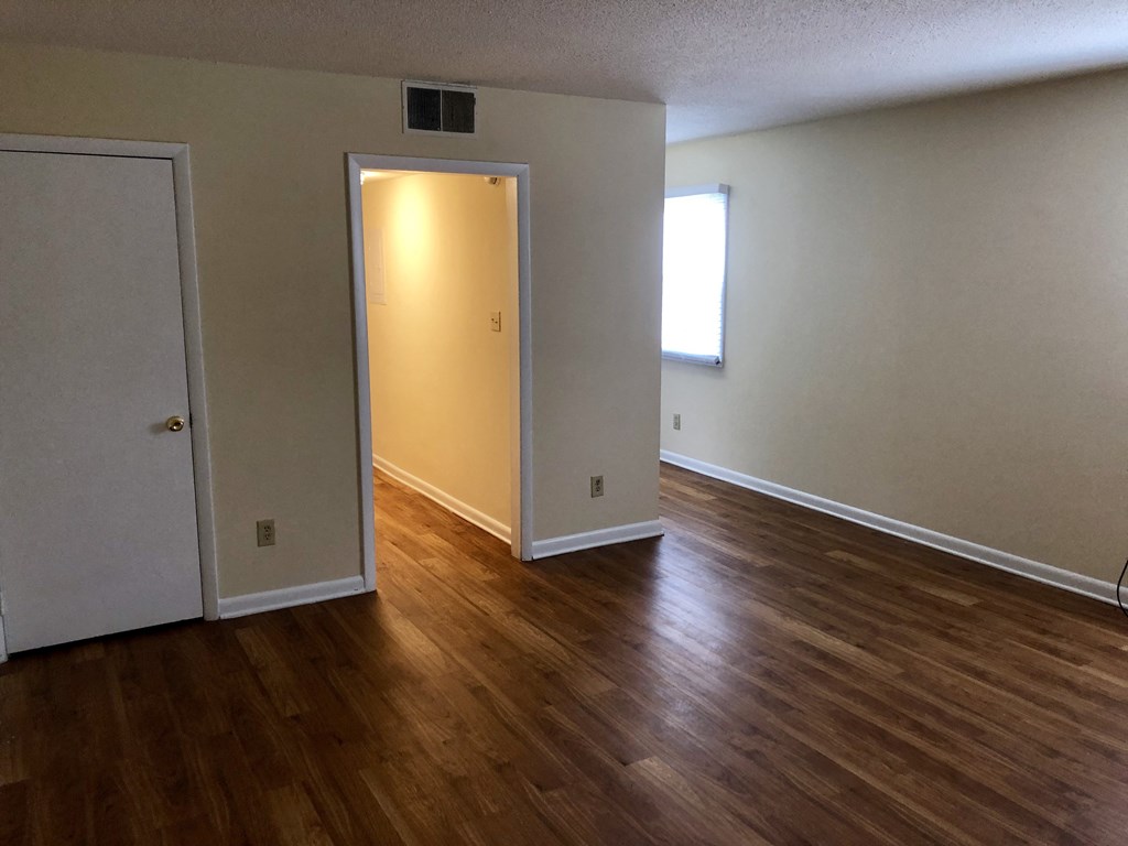 an empty living room with wood floors and a door