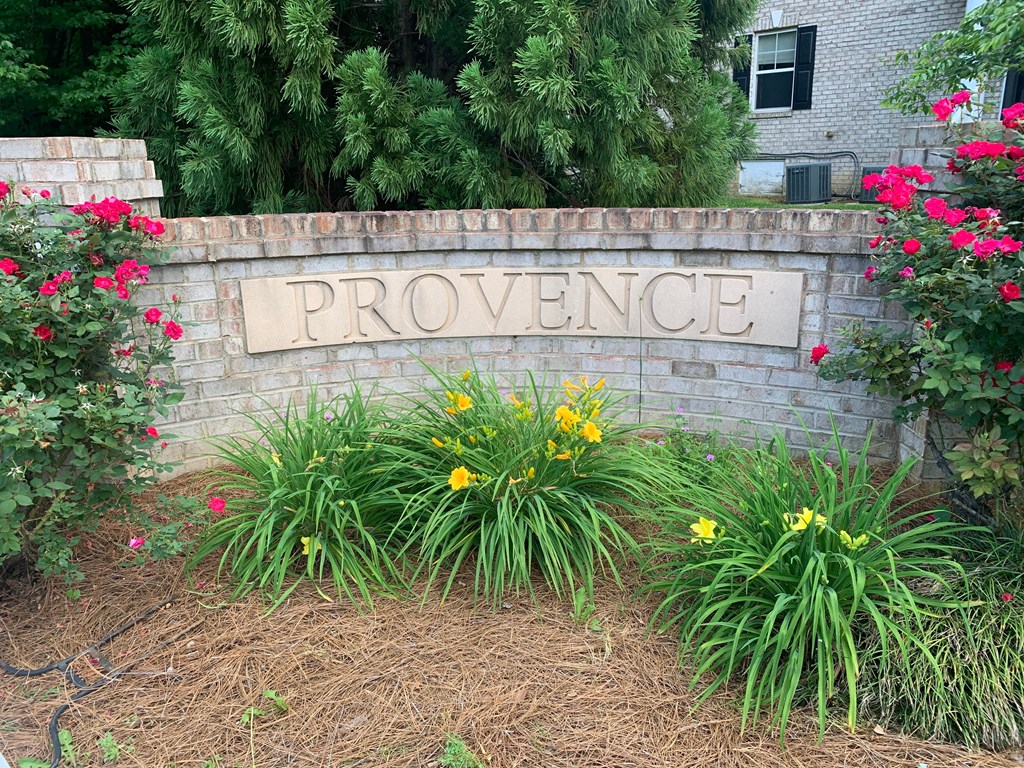 a brick wall with a providence sign in front of flowers