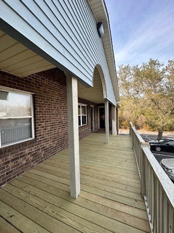 a porch of a brick house with a wooden deck