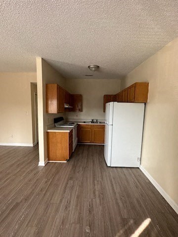an empty kitchen with a white refrigerator and cabinets
