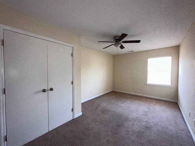 an empty living room with a ceiling fan and a closet