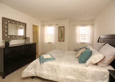 A bedroom with a bed, dresser, and mirror.