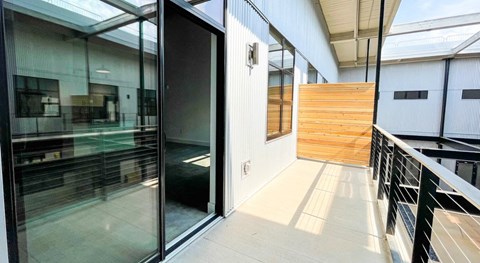 A glass door is open to a hallway with a wooden wall at Judson Mill Lofts and The Jenny & Westervelt in Greenville, SC