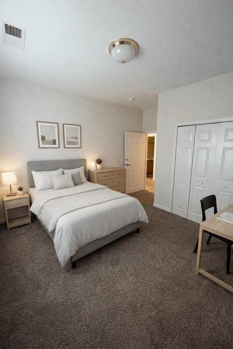 A bedroom with a bed, nightstands, and a chair.