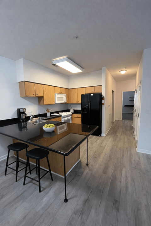 A kitchen with a black countertop and a black fridge.