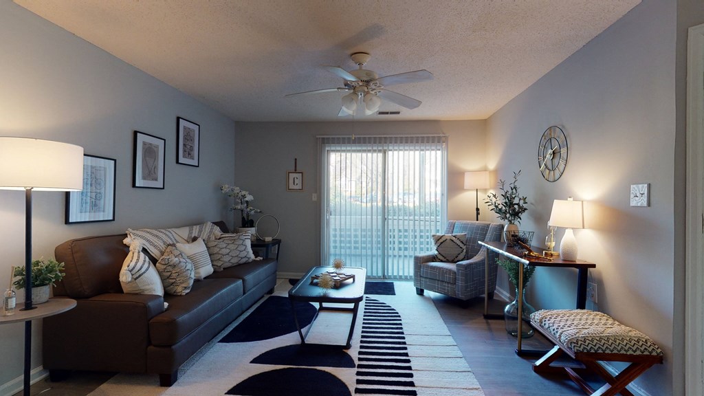 a living room with couches and chairs and a ceiling fan