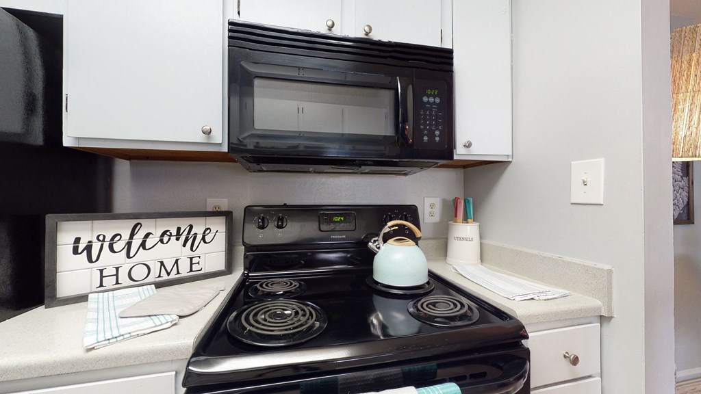 a kitchen with a stove and microwave and a sign that says welcome home