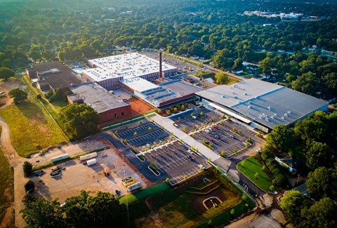 An aerial view of a large building complex surrounded by trees. at Judson Mill Lofts and The Jenny & Westervelt in Greenville, SC