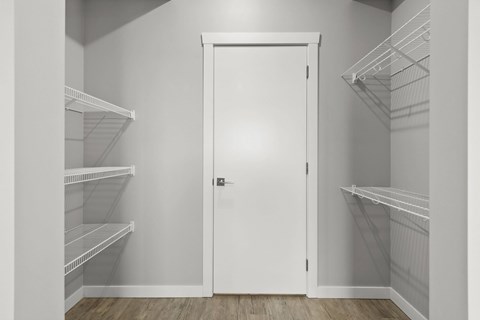 A white door is in the middle of a room with shelves on the walls.