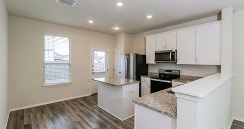 A kitchen with white cabinets and a granite countertop.