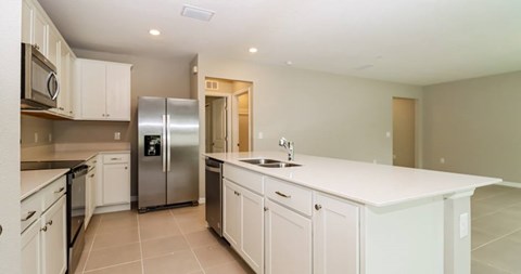 A kitchen with white cabinets and a stainless steel refrigerator.