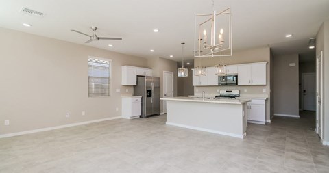 A spacious kitchen and living room with a ceiling fan and modern lighting fixtures.
