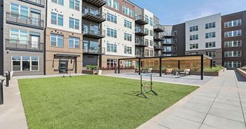a grassy area with a swing set in front of an apartment building