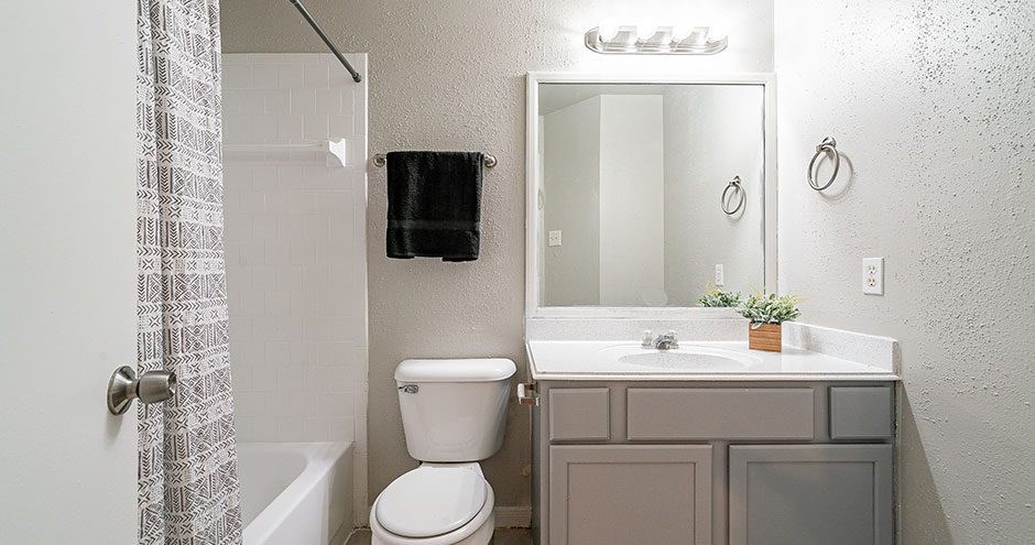 A white toilet sits under a mirror in a bathroom.