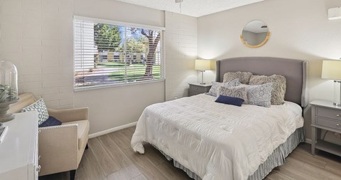 A bedroom with a large bed and a chair.