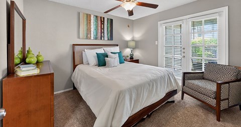 A bedroom with a bed, chair, and a dresser.