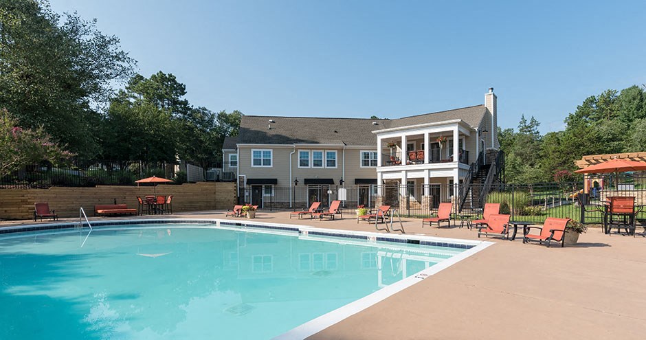 a swimming pool with chairs and a building in the background