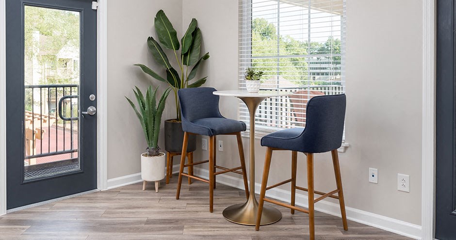 a living room with two stools at a table and a door to a balcony