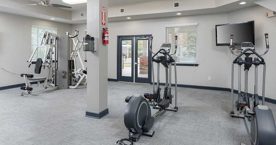 a gym with exercise equipment and a tv in it