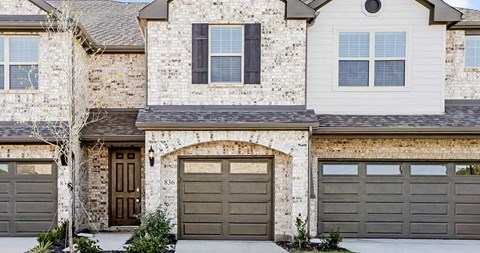a white brick house with two garage doors