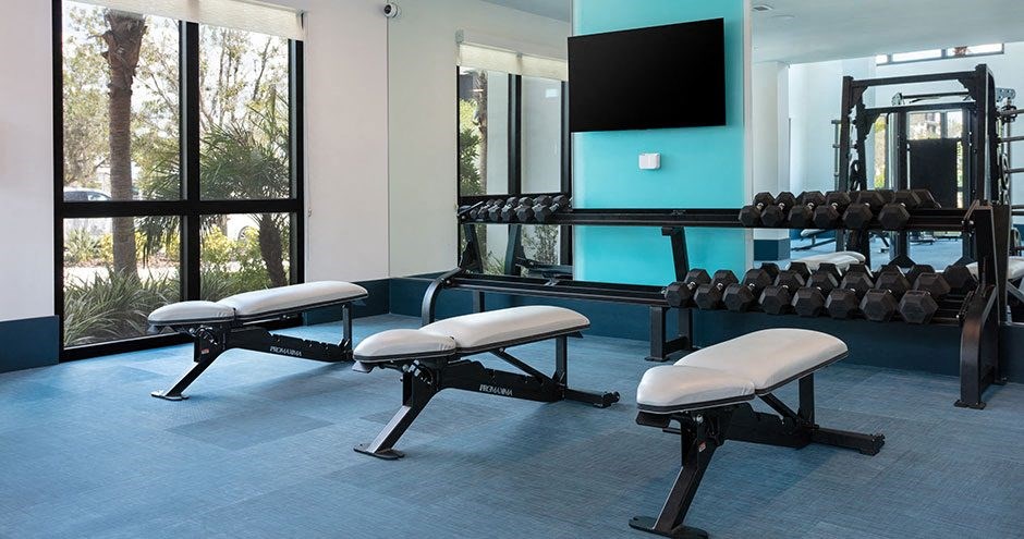 a fitness room with weights and benches and a television
