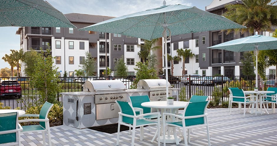 a patio with a grill and tables with umbrellas