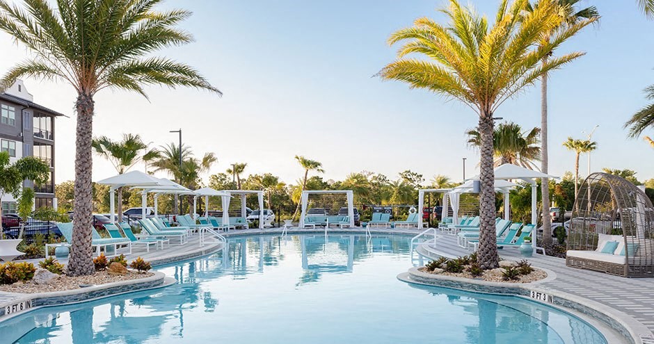 a large swimming pool with chairs and palm trees