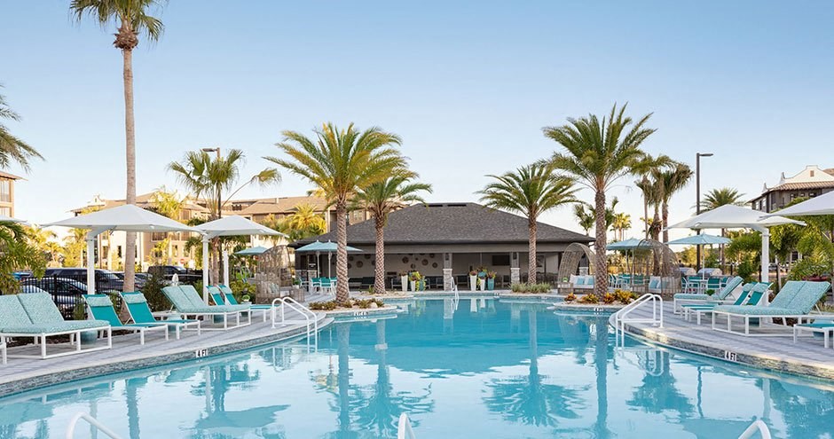 a large swimming pool with chairs and palm trees
