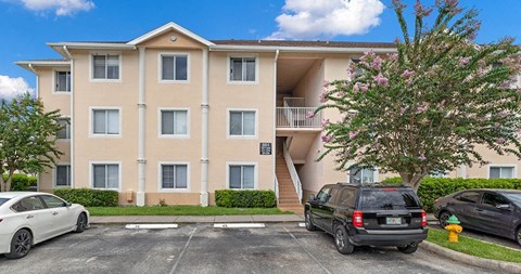 an apartment building with cars parked in a parking lot