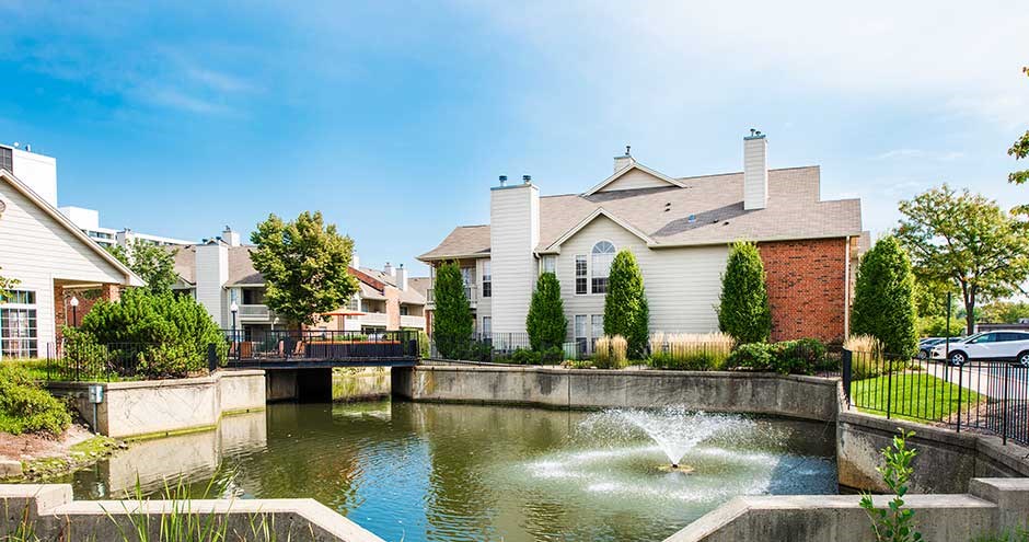 a pond with a fountain in front of a house