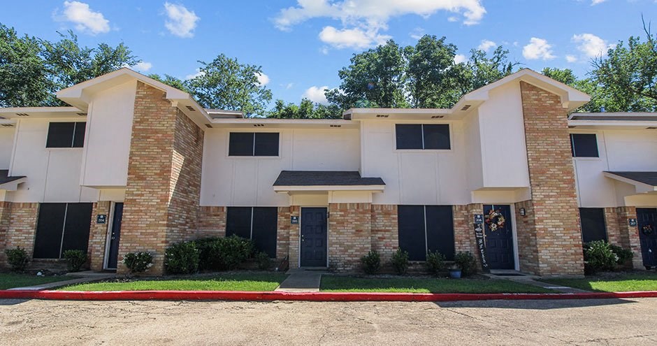 a white building with a sidewalk and grass