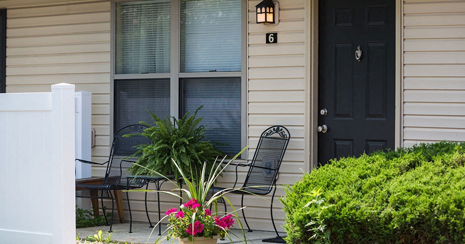 a front porch with two chairs and a black door