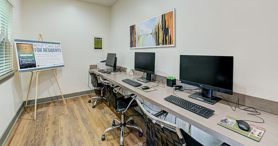 a computer room with three monitors on a long desk