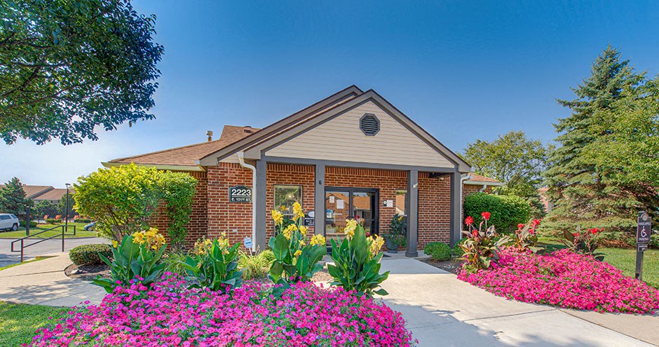 the front of a brick building with a sidewalk and flowers