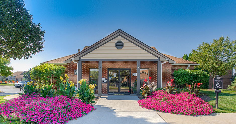 the front of a brick building with a sidewalk and flowers