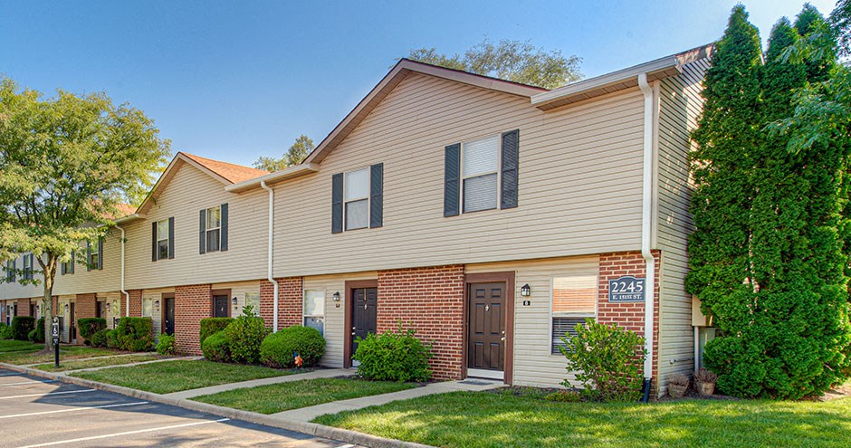 an apartment building with a sidewalk and grass