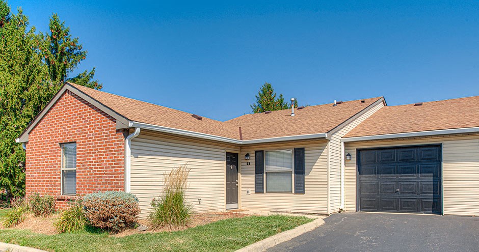 the front of a yellow house with two garage doors
