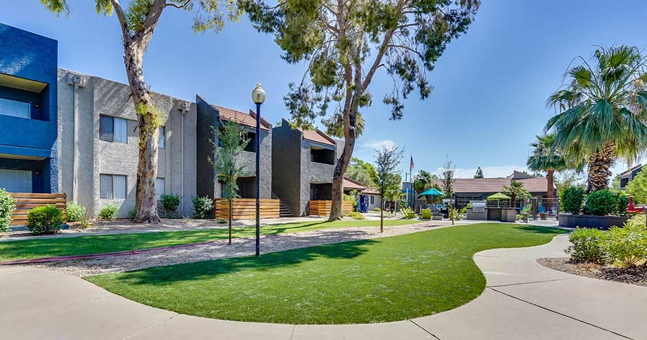 a sidewalk in front of a building with grass and trees
