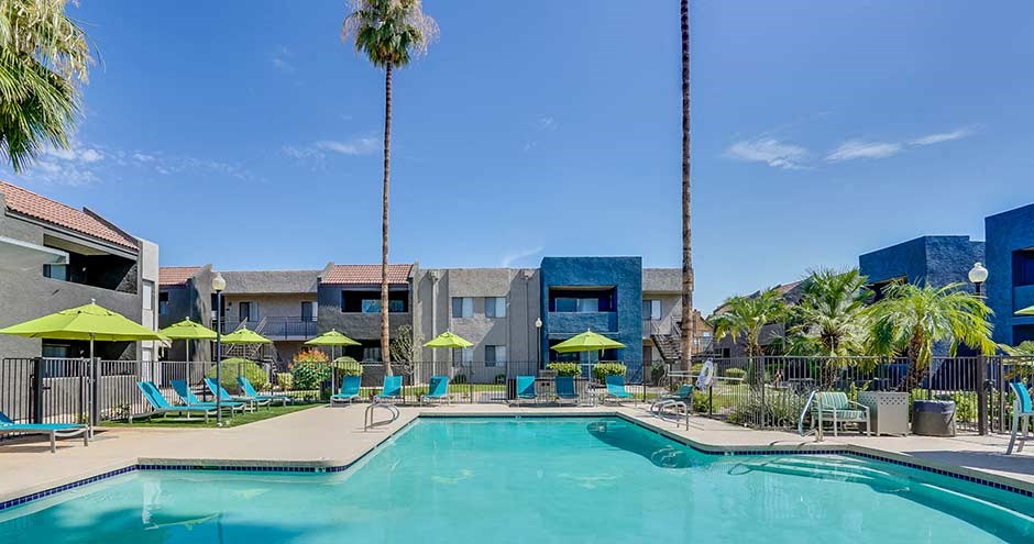 a swimming pool with blue chairs and yellow umbrellas