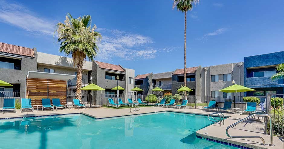 a large swimming pool with blue chairs and yellow umbrellas