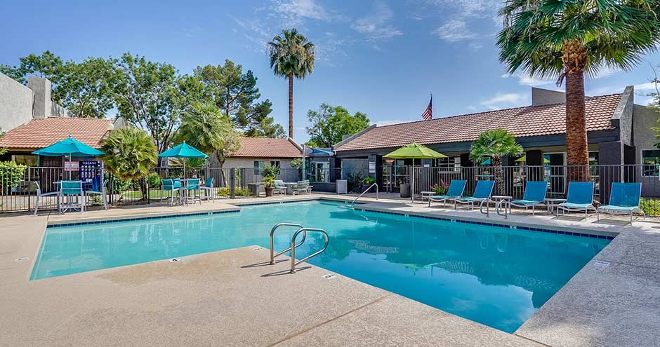 a swimming pool with blue chairs and palm trees