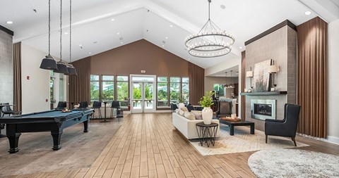 A well-lit, spacious living room with a pool table and a fireplace.