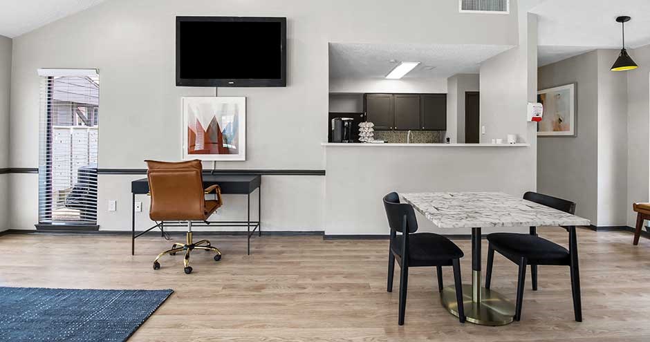 a room with a table and chairs and a television on the wall
