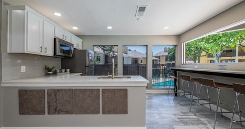 A kitchen with a white counter top and a window overlooking a pool.