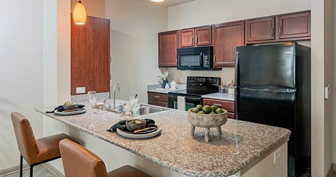 a kitchen with a granite counter top and a black refrigerator