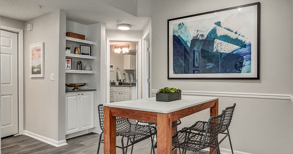 a dining room with a table and chairs and a painting on the wall