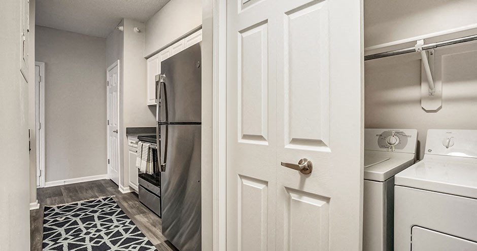 a white door opens to a laundry room with a refrigerator