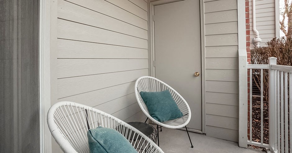 the front porch of a house with two chairs and a door