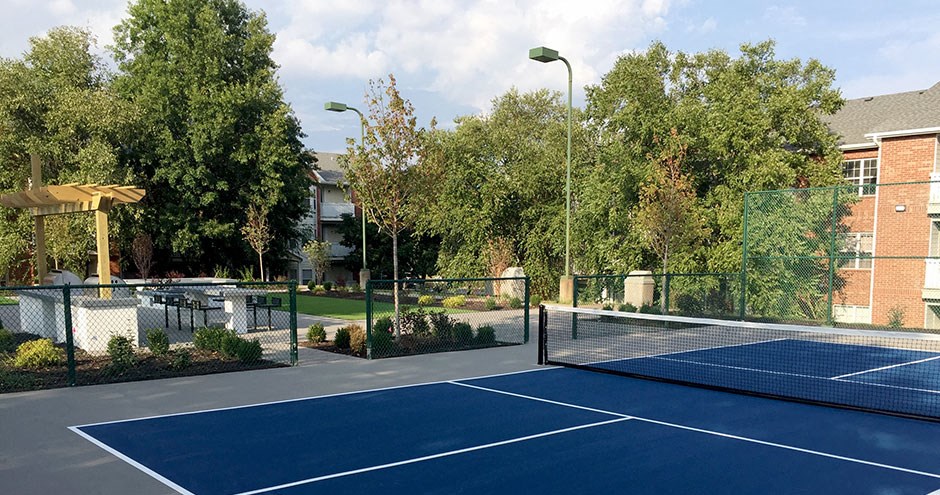 a tennis court with a fence and trees